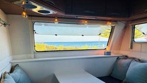 En ombonad inredning med en fönsterplats, ett bord och utsikt över havet.
