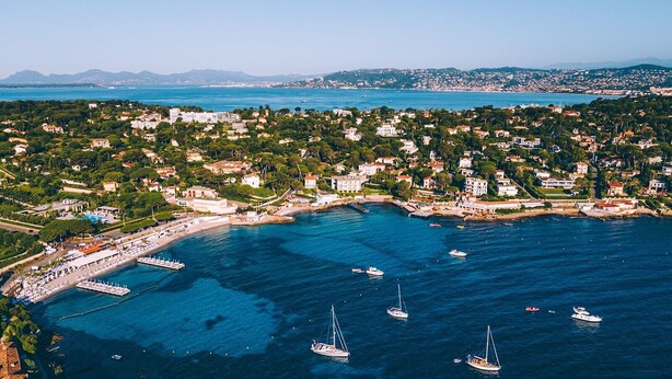 Vue aérienne d’une ville côtière avec un port de plaisance, des bateaux et des immeubles résidentiels.