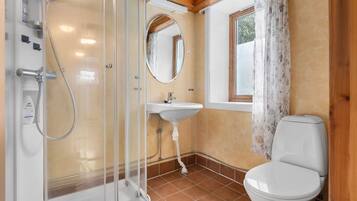Ein Badezimmer mit Duschkabine aus Glas, einem Standwaschbecken, einer Toilette und einem Fenster mit Blick.