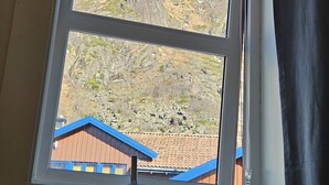 A window with a view of a mountain and a building with a red roof. - Apartment close to the mountain - free parking (Nordland)