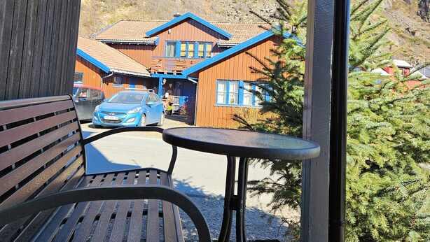 A wooden bench and table under a shelter with a mountain view. - Apartment close to the mountain - free parking (Nordland)