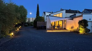 A modern house with a covered patio, a gravel driveway, and a moonlit sky.