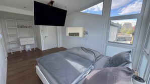 A bedroom with a bed, a wardrobe, a TV, and a window with a view.