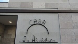 Entrada de un edificio con un letrero metálico que dice 'CASA La Alcachola'.