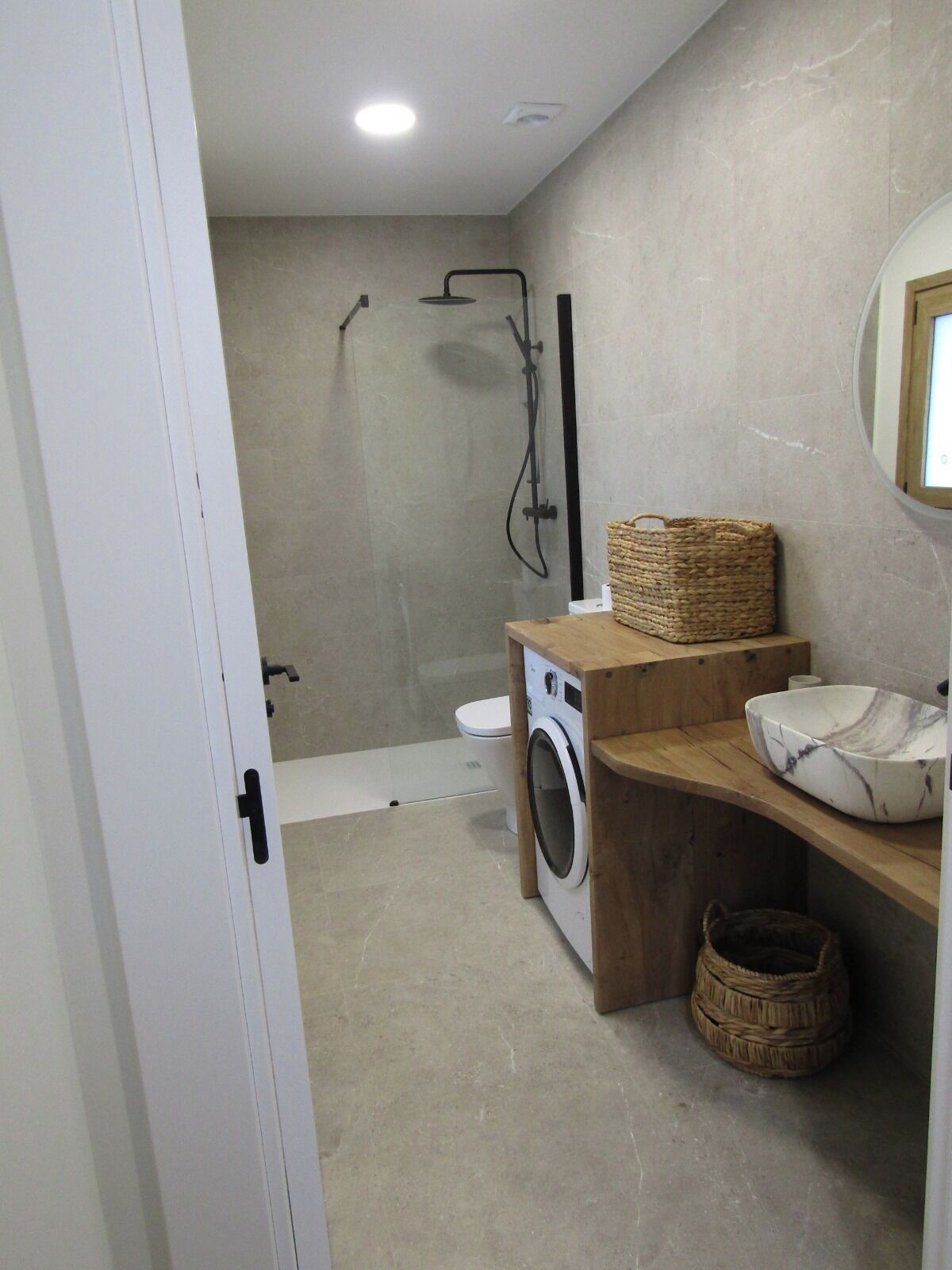 Une salle de bain moderne équipée d’une douche, de toilettes et d’un lave-linge.