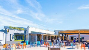 Ein Restaurant mit Außenbereich und einem Foodtruck mit der Aufschrift 'Thunderbird Fried Chicken'.