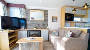 Ein gemütlicher Wohnbereich mit Flachbildfernseher, Kamin, Küchenzeile und einer Couch.