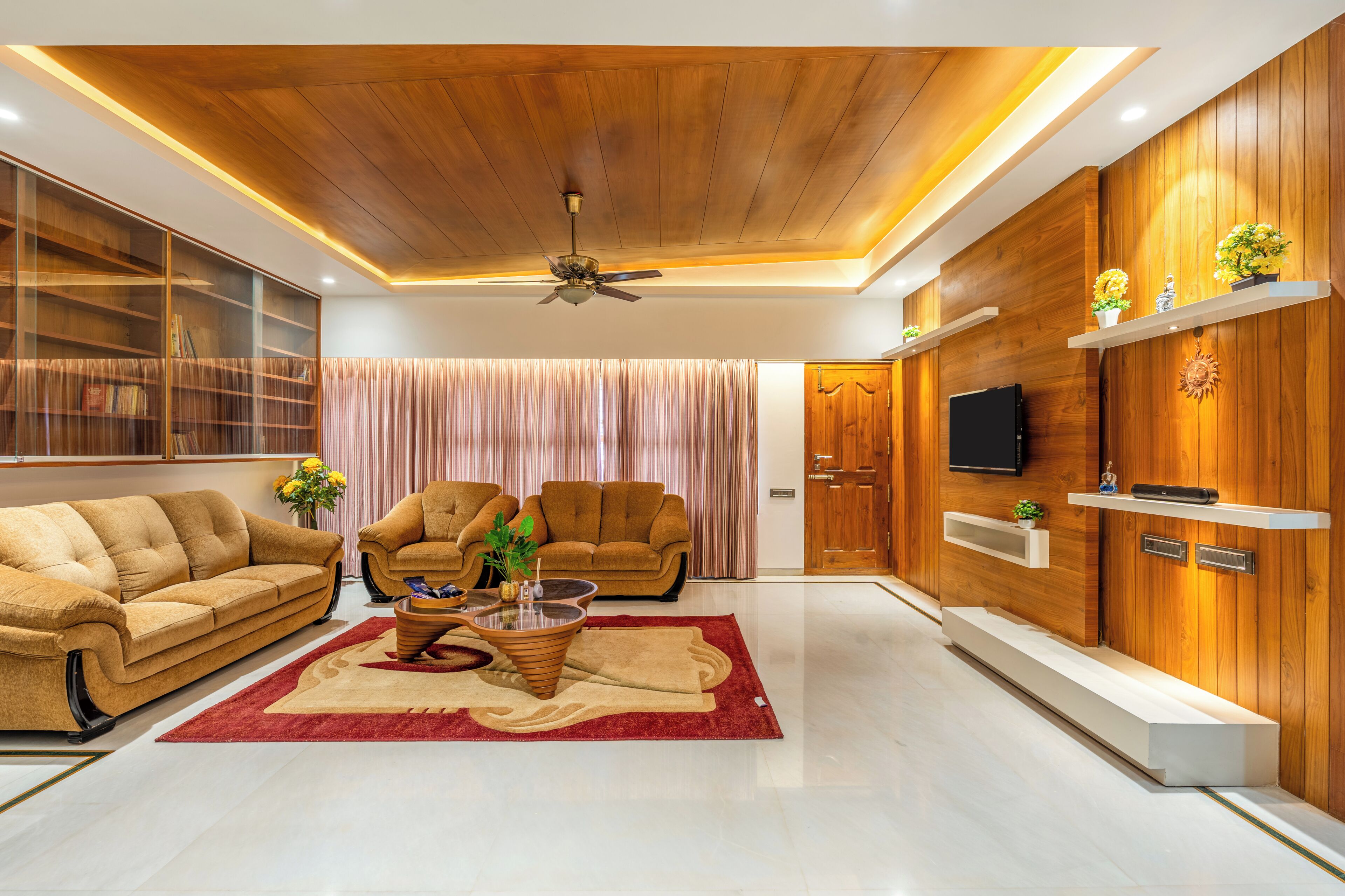 A modern living room with a sofa, armchairs, a coffee table, and a TV mounted on a wooden wall.