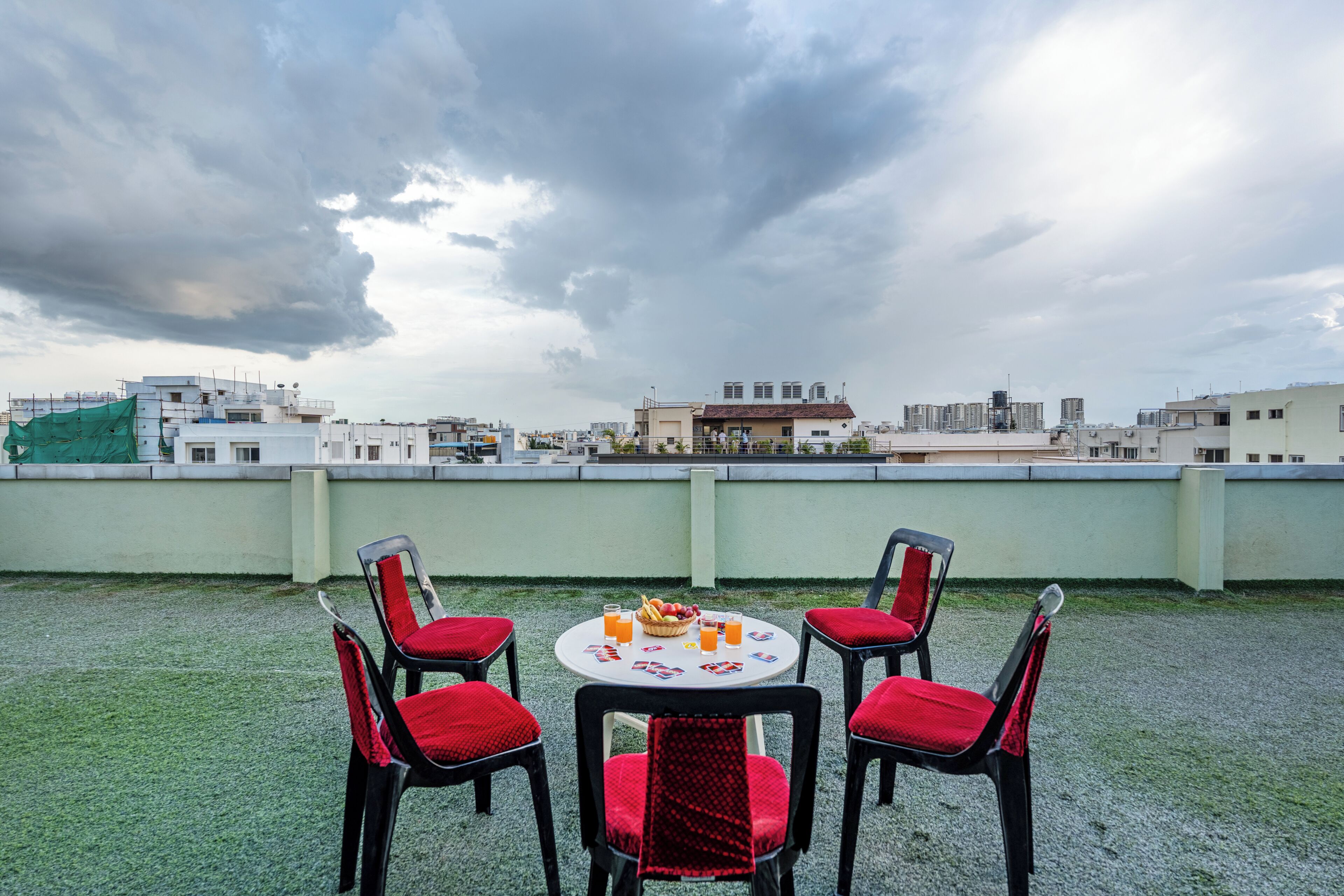 Eine Dachterrasse mit einem runden Tisch, vier Stühlen, einer Obstschale und Getränken.