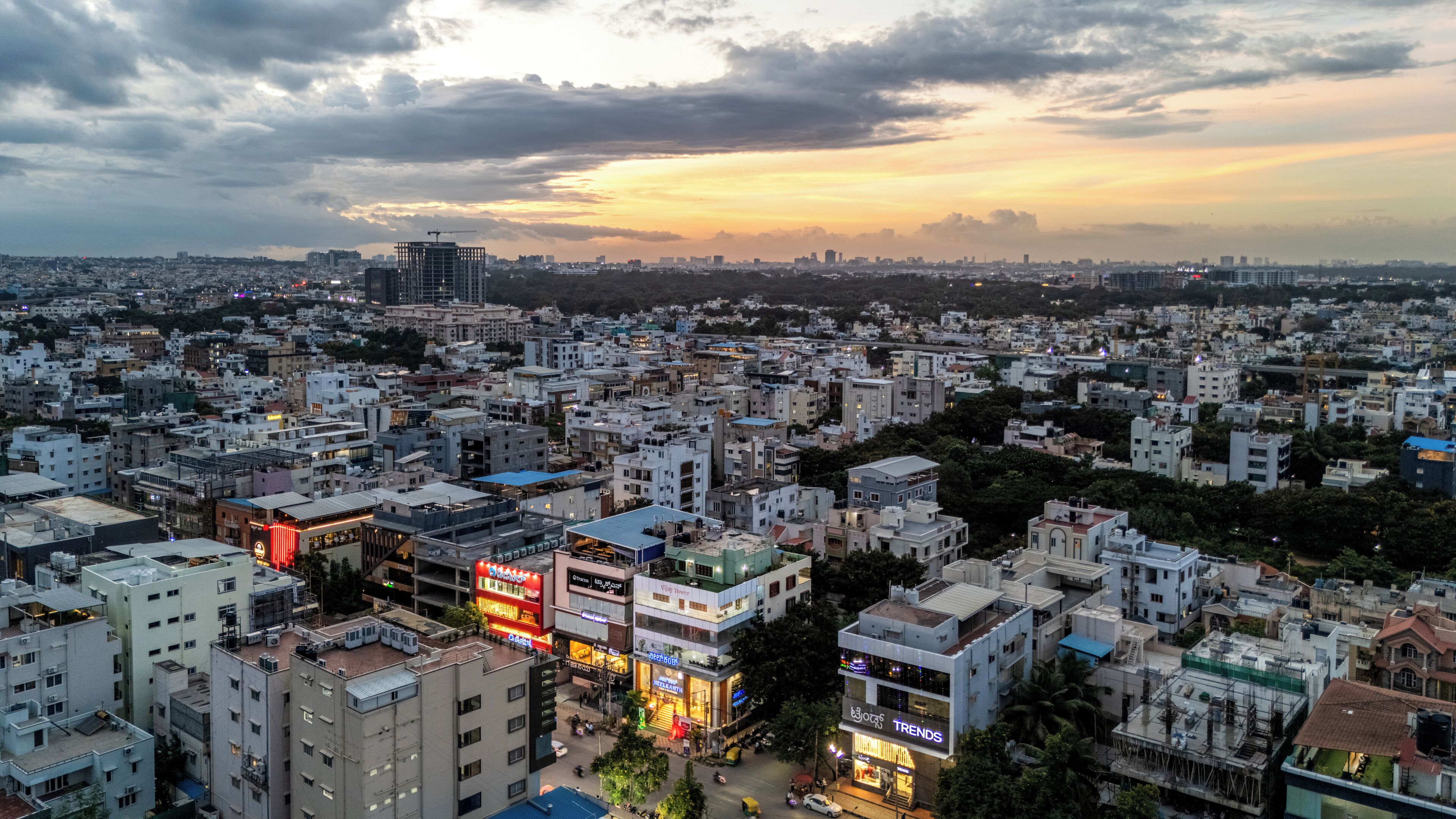 A cityscape with densely packed buildings, a prominent construction crane, and a sunset sky.