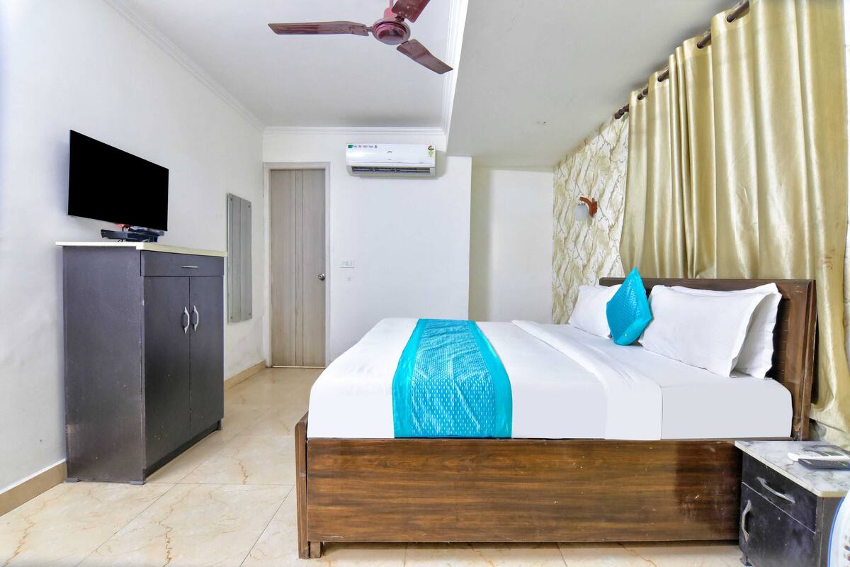 Une chambre d’hôtel équipée d’un lit, d’une télévision, d’une armoire, d’un climatiseur et d’un ventilateur de plafond.