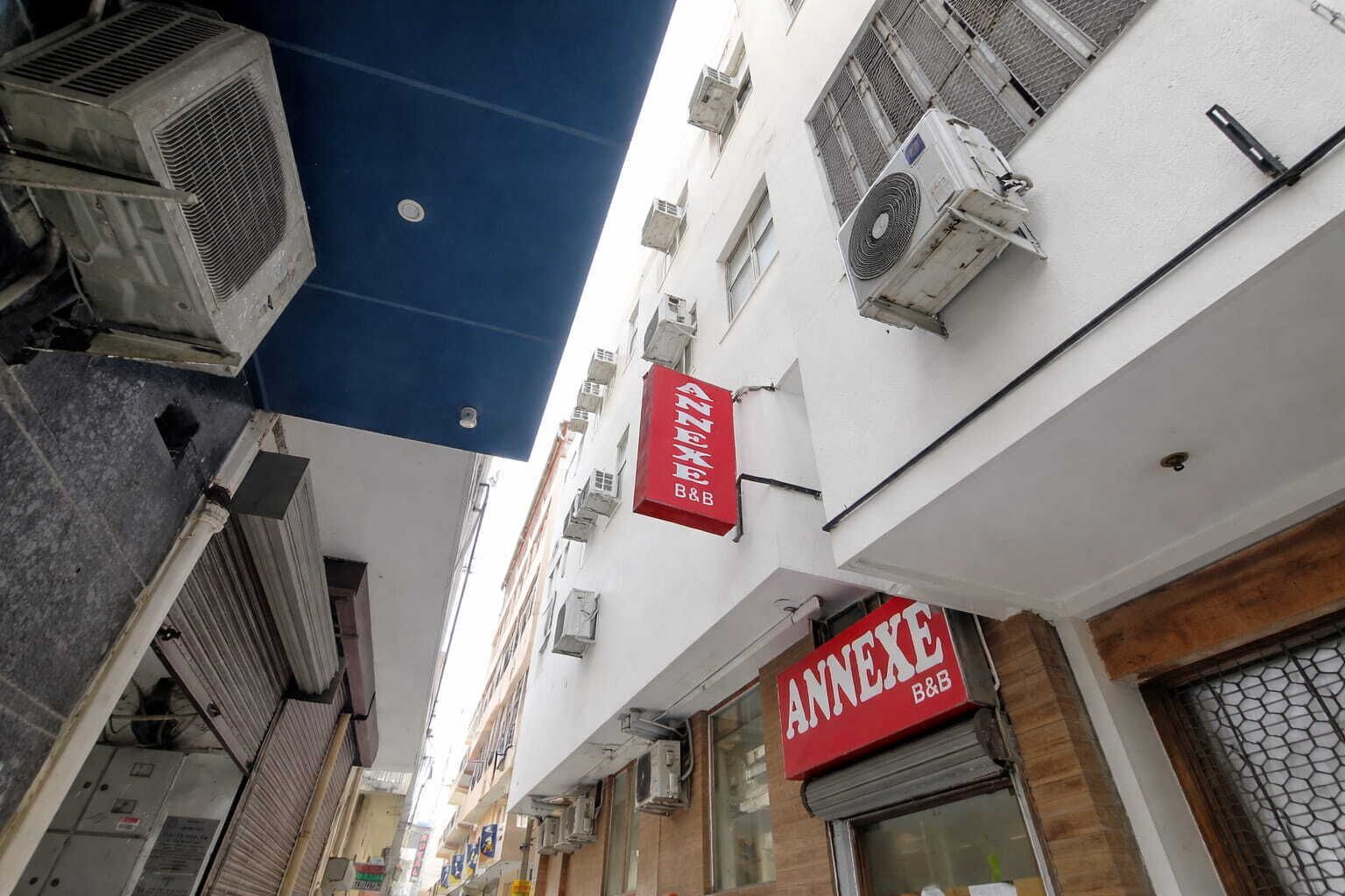 Un bâtiment doté de plusieurs unités de climatisation, d’une enseigne rouge indiquant « ANNEX B&B », et dont la devanture est bien visible.