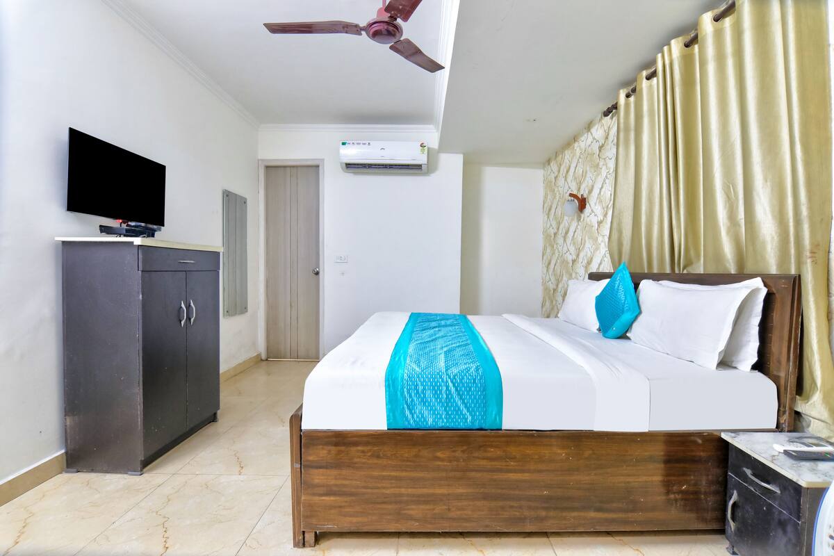 Une chambre d’hôtel équipée d’un lit, d’une télévision, d’une armoire, d’un climatiseur et d’un ventilateur de plafond.