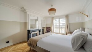 Una camera da letto con un letto, un camino, uno specchio e una finestra con tende.