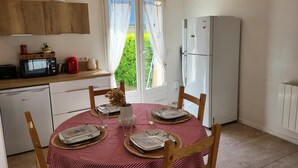 Una cocina compacta con comedor, refrigerador, microondas y cafetera.