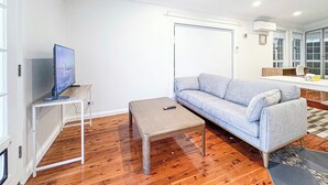 Un salon avec un canapé, une table basse et un téléviseur posé sur un meuble.