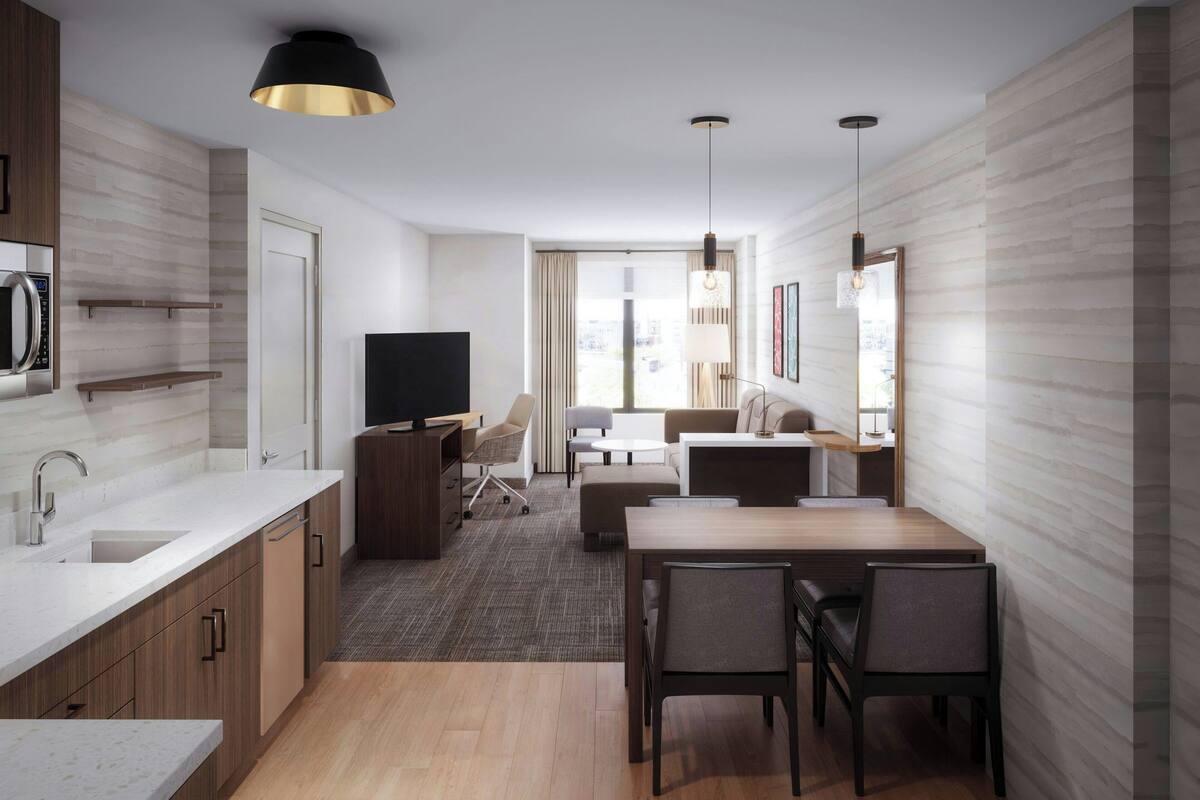 A modern kitchen with a microwave, a flat-screen TV, and a dining area with a table and chairs.