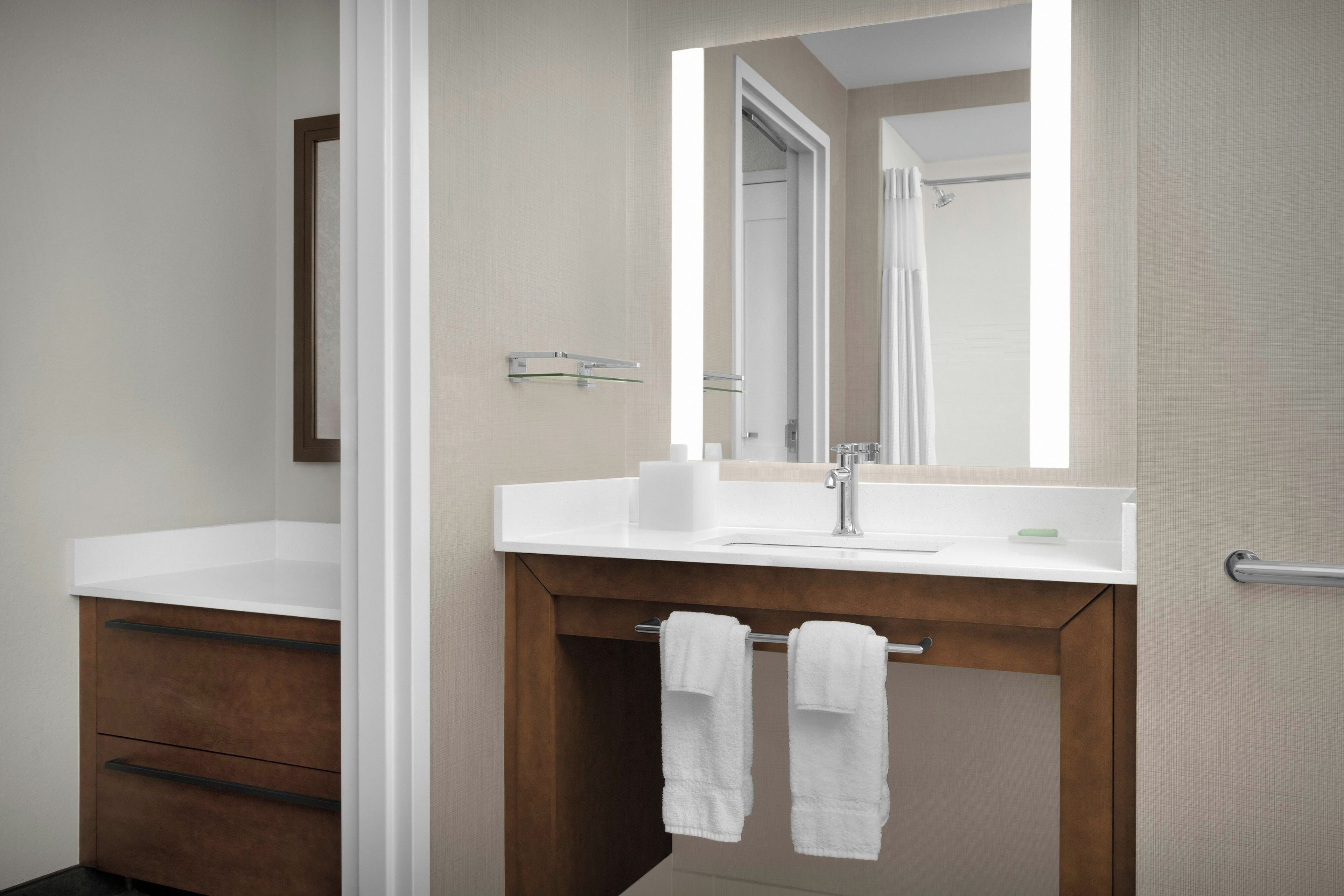 Un baño moderno con un lavamanos blanco, un espejo y un perchero para toallas.