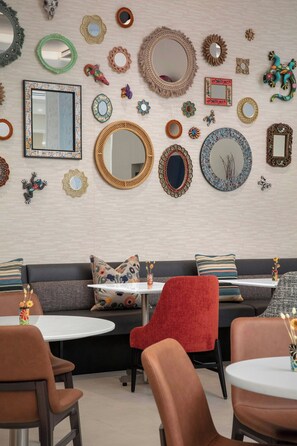 A room with a variety of decorative mirrors and wall art, a sofa with patterned cushions, and a red chair. - Residence Inn by Marriott San Antonio Riverwalk (San Antonio)