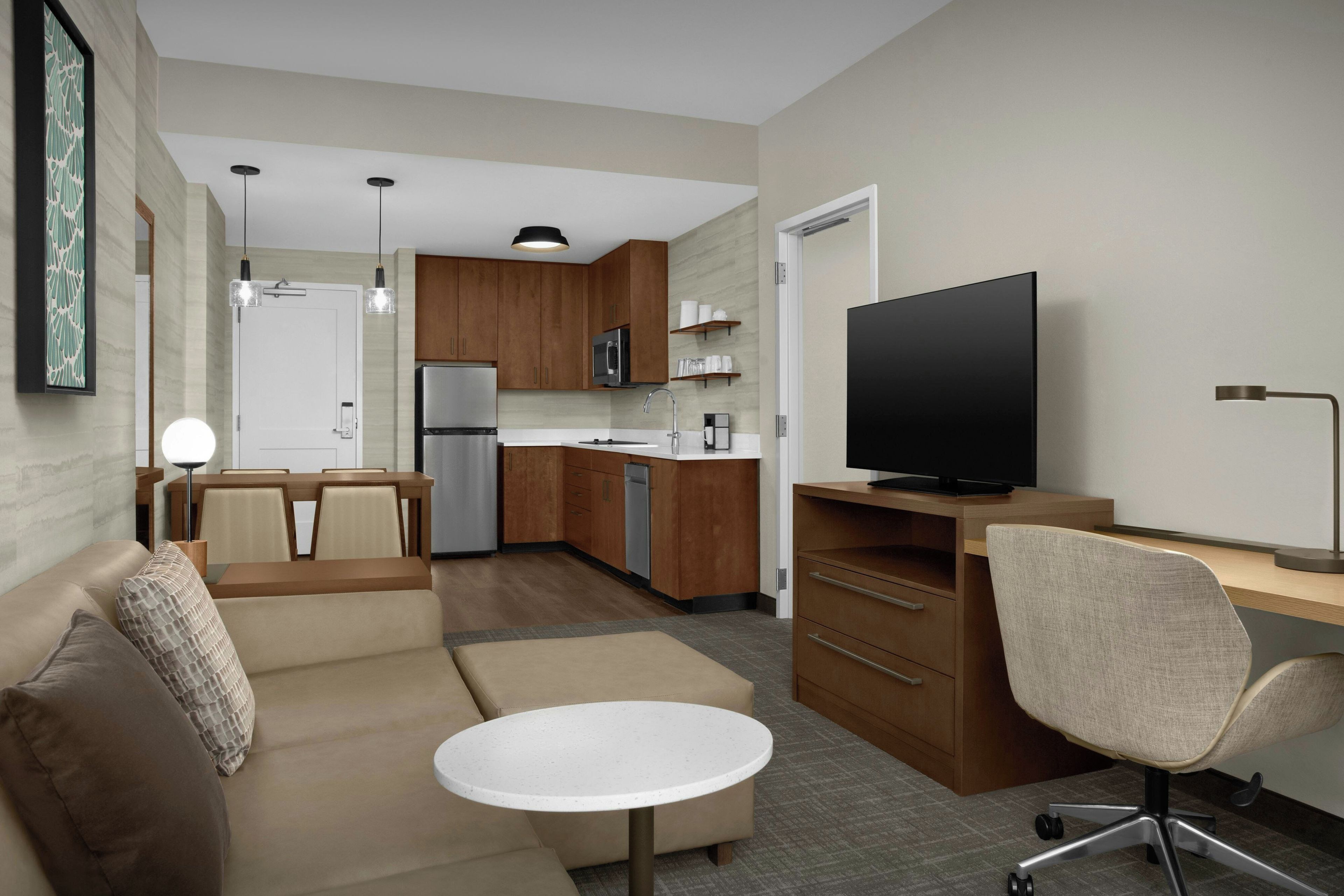 A compact living space with a kitchenette, a sofa, a dining table, and a TV.