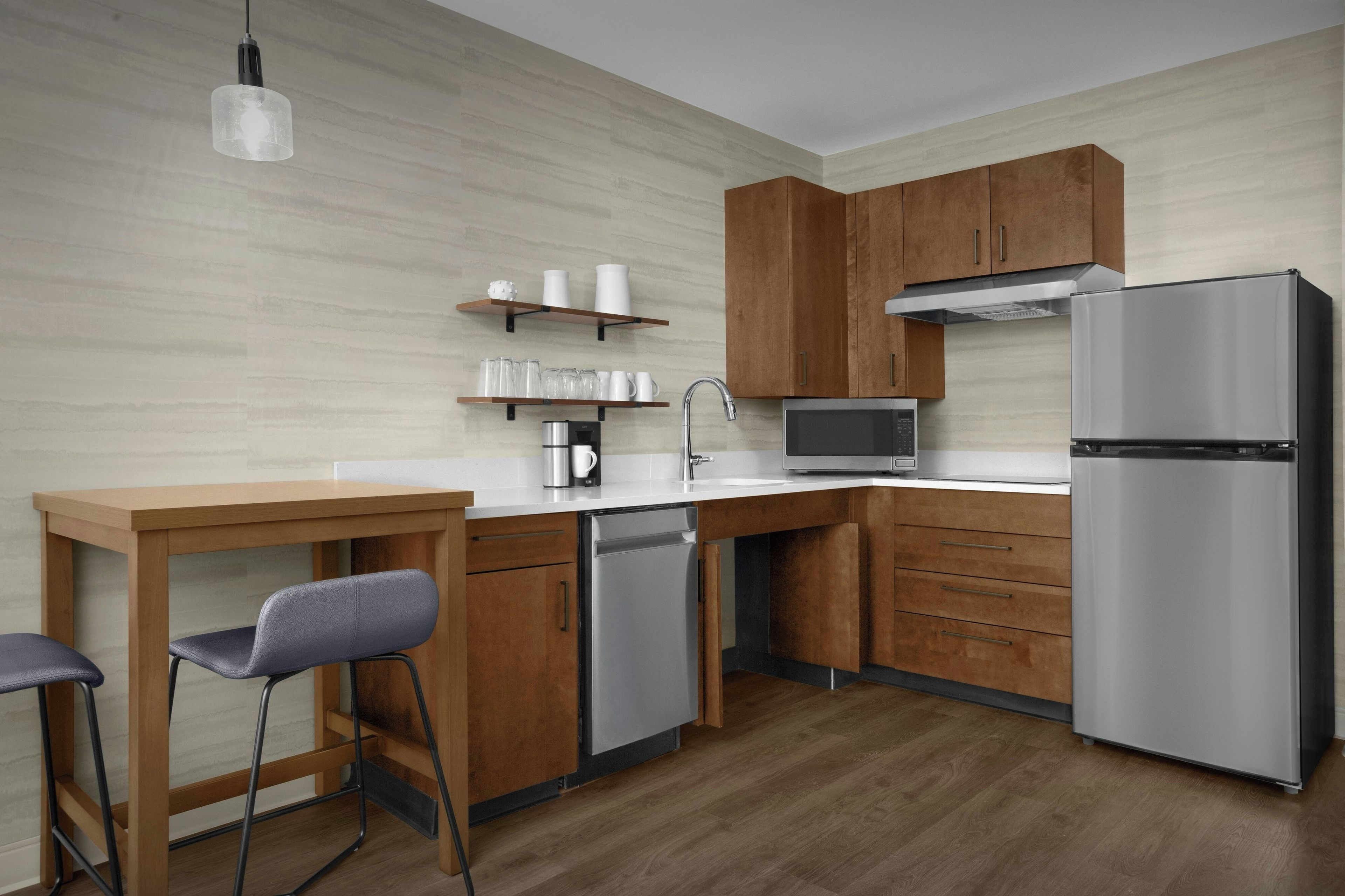 Una cocina moderna con armarios de madera, un refrigerador de acero inoxidable, un microondas y una cafetera.