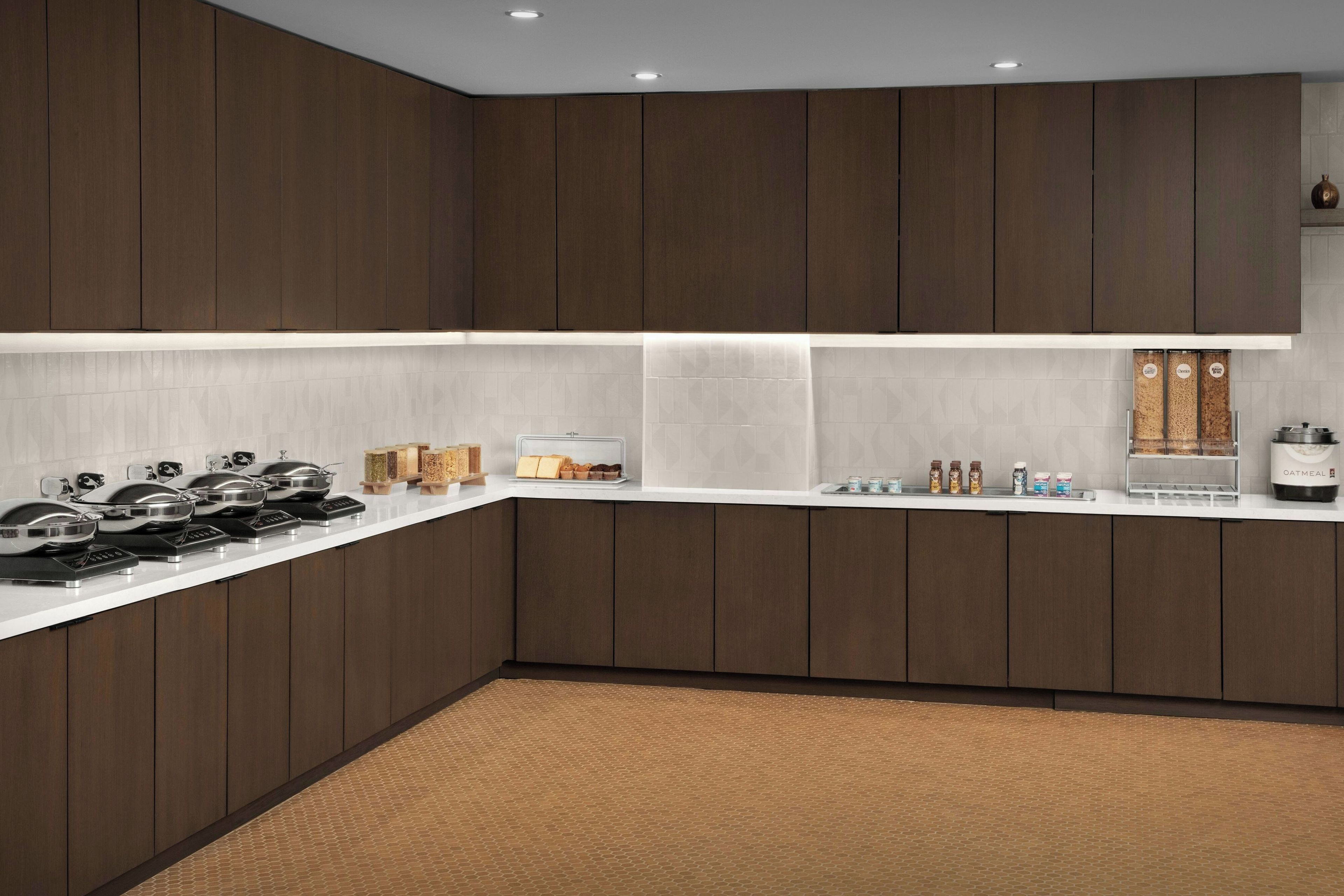 A modern kitchen with dark wood cabinets, a white countertop, and various appliances.
