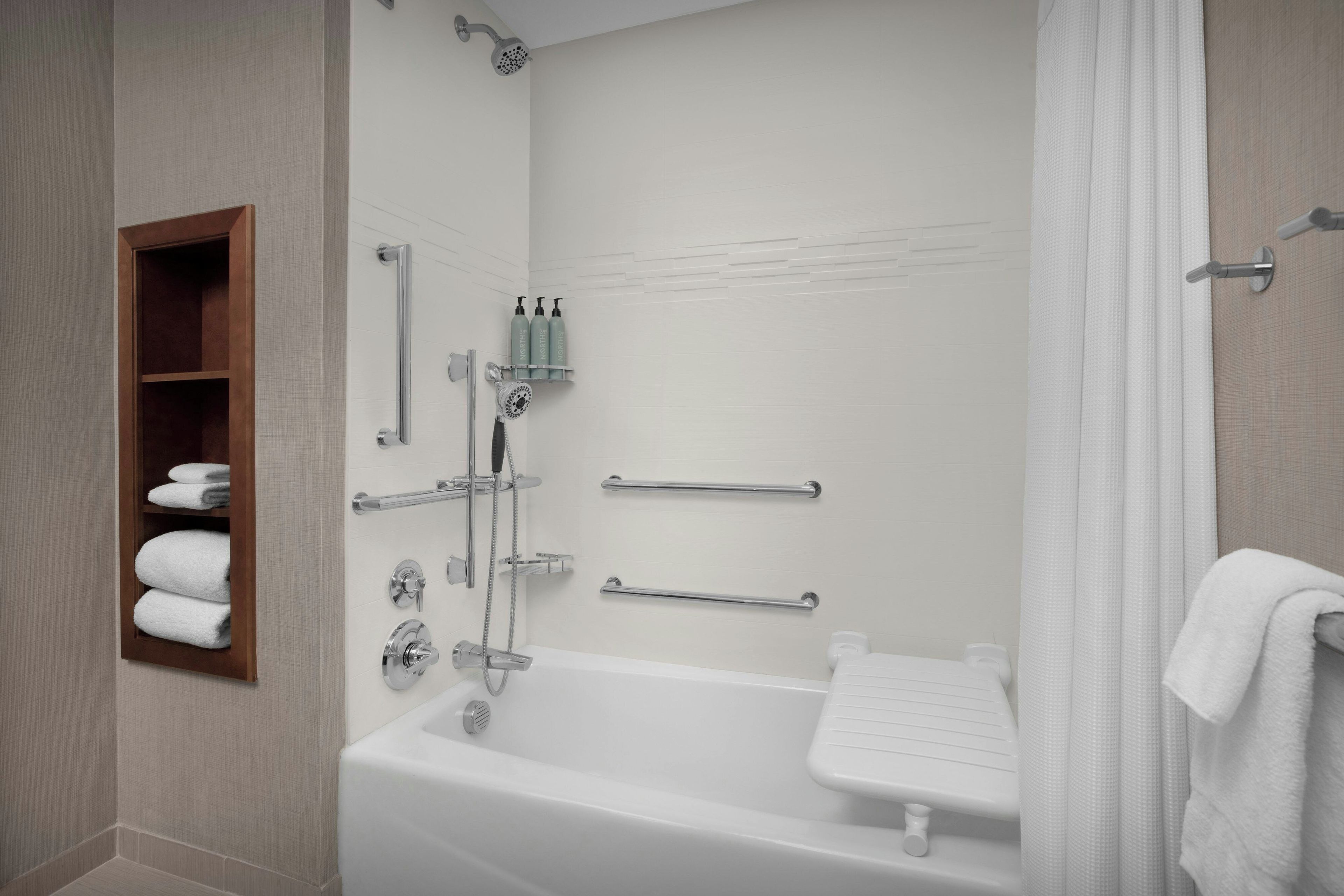 A modern bathroom with a bathtub, shower, and a towel rack.