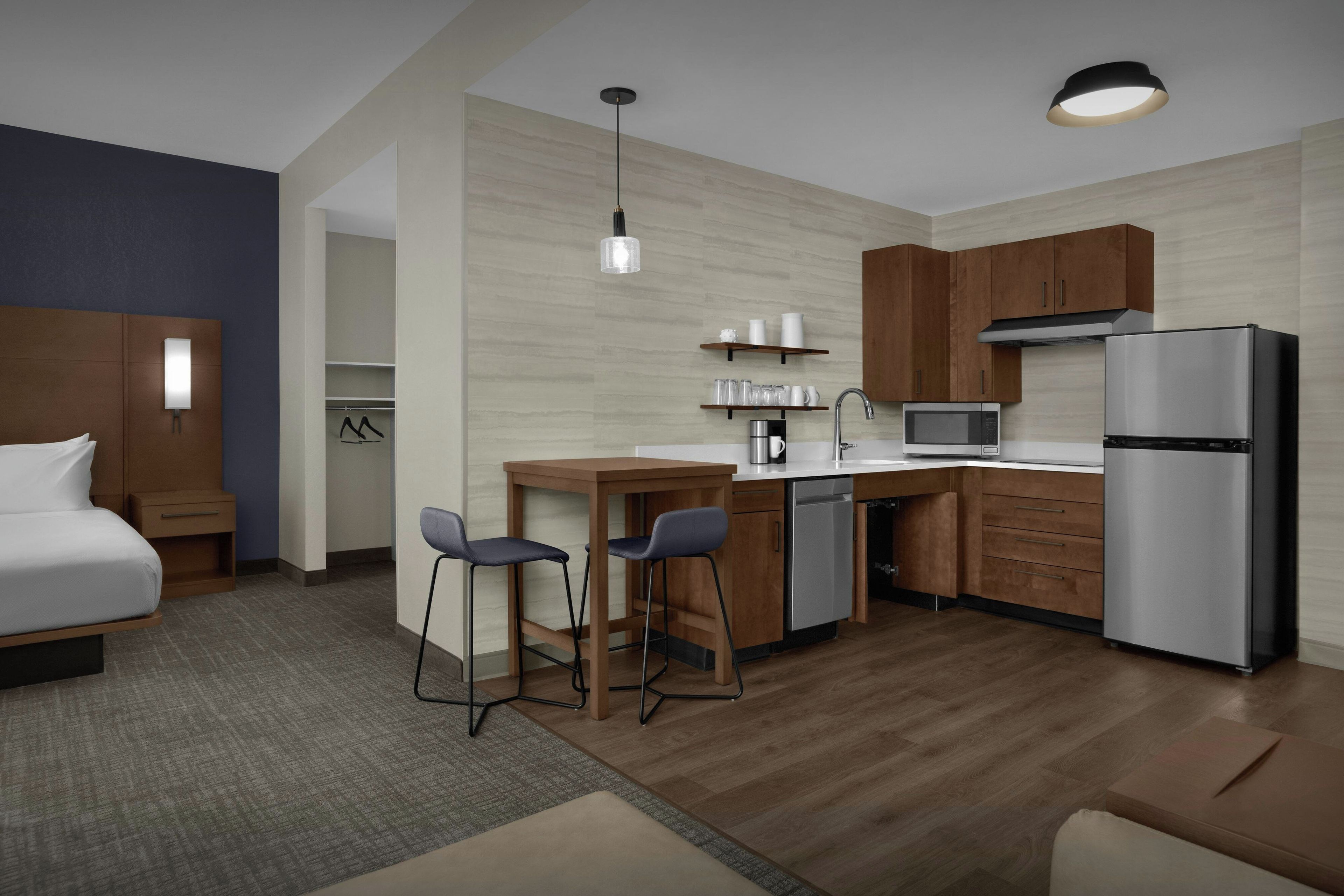 Habitación de hotel compacta con cama, kitchenette y un pequeño comedor.