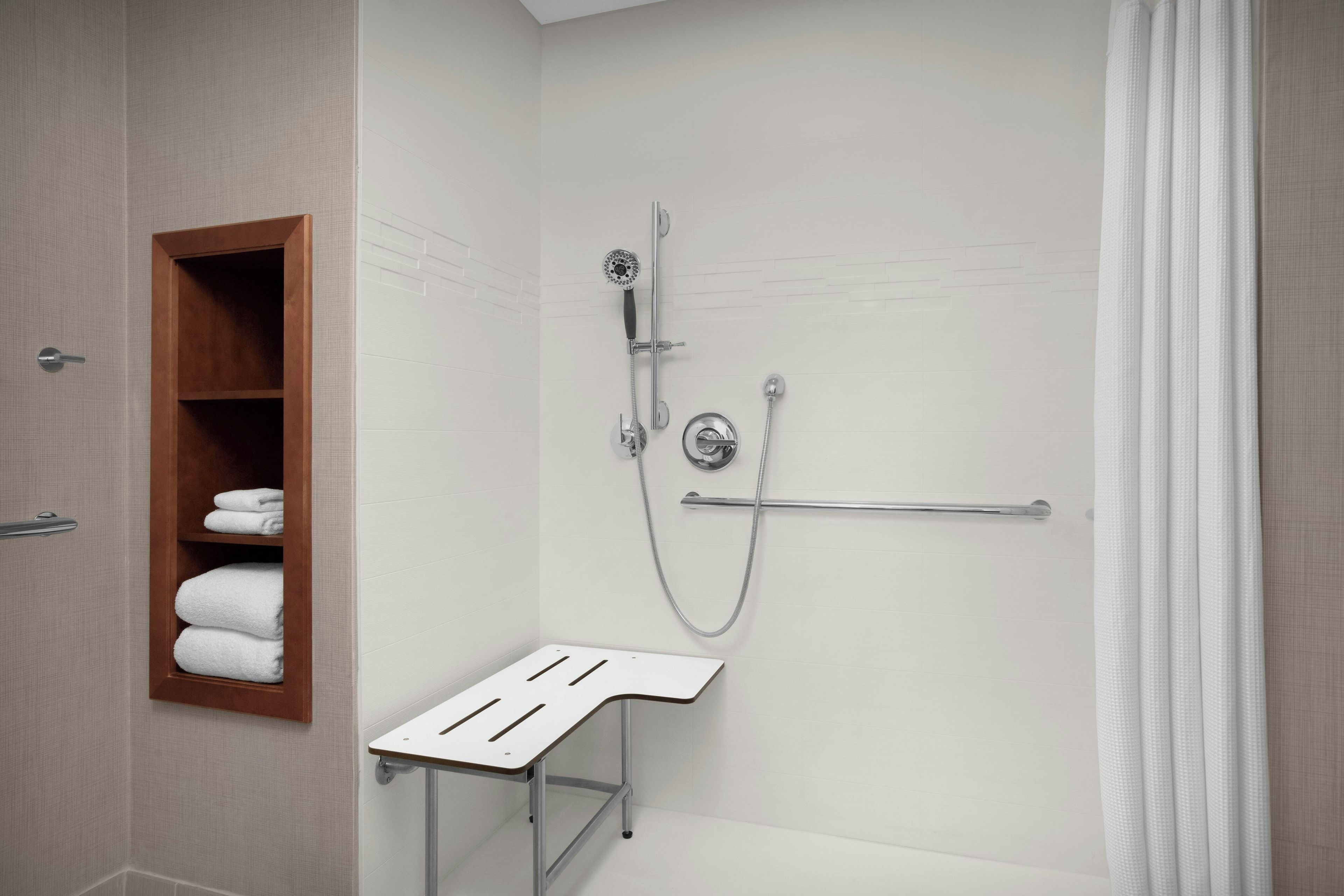 Un espace douche équipé d’un pommeau de douche à main, d’un porte-serviettes et d’une petite table.