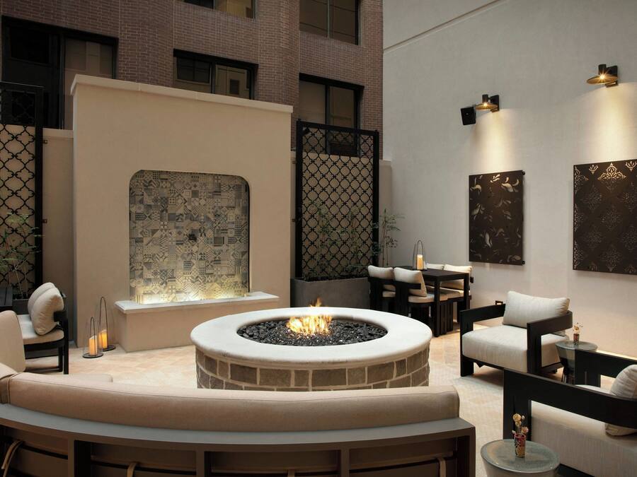 A modern outdoor seating area with a fire pit, cushioned seating, and decorative wall art.