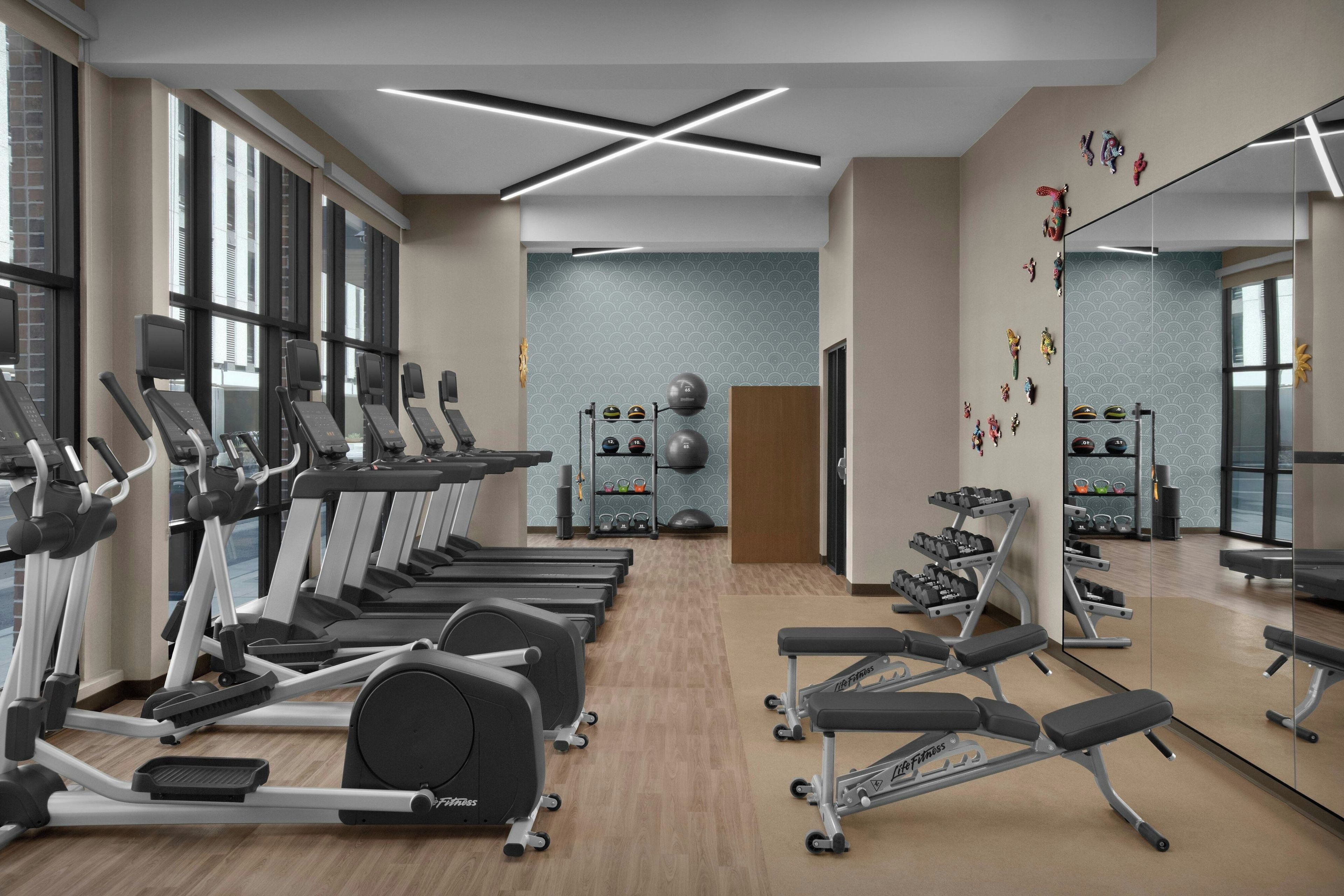 Une salle de sport équipée de tapis de course, d’appareils de musculation et d’un mur recouvert de miroirs.