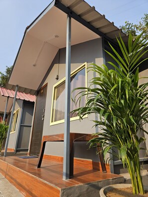 A modern house with a covered porch, a large window, and a potted plant. - magic stone resort (Shivpuri)