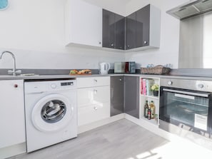 A modern kitchen with a washing machine, microwave, and oven. - Bliss (Lytham St. Anne's)