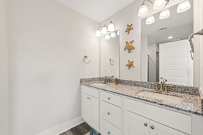 A bathroom with a white vanity, a large mirror, and a sink with a granite countertop. - Amazing 3-bedroom townhome steps from beach and many attractions PCB (Panama City Beach)