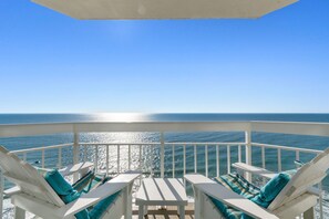 A balcony with white railings, two white lounge chairs with teal cushions, and a small table. - Rising Tides Properties Condo 1506 (Murrells Inlet)