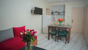 A compact living space with a sofa, a dining table with chairs, a kitchen area, and a flat-screen TV mounted on the wall. - Apartment downtown Agadir 10 min from the beach (Agadir)