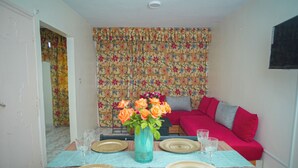 A dining area with a table set for four, a vase with flowers, and a red sofa in the background. - Apartment downtown Agadir 10 min from the beach (Agadir)