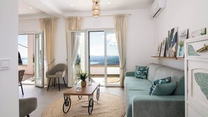 Ein modernes Wohnzimmer mit Sofa, Esstisch und Stuhl. Ein Balkon mit Blick.