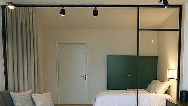 Ett rum med en säng, en soffa, ett skrivbord och en dörr.