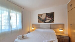 Una habitación de hotel con una cama, dos lámparas de noche, un cuadro en la pared y una ventana con cortinas.