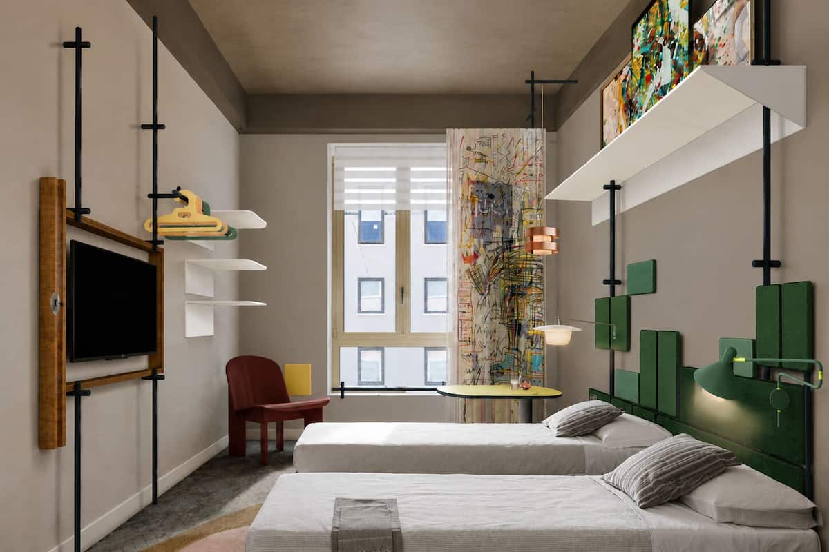 A modern hotel room with two beds, a TV, a desk, and artwork on the walls.