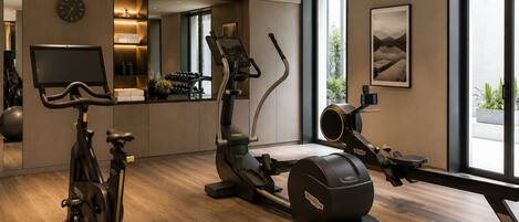A modern home gym with exercise equipment, a TV, and a large window.