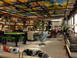 A modern interior with a bar area, seating, and a ceiling with graffiti art. - Ibis Styles Saint Germain En Laye (Saint-Germain-en-Laye)