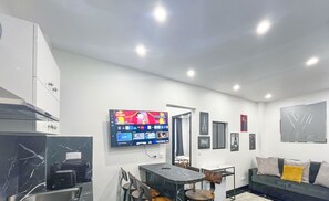 Un salon moderne avec un téléviseur à écran plat, une table à manger et un canapé.