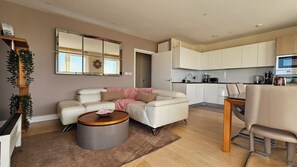 En moderne stue med sofa, sofabord og et spiseområde med en stol.