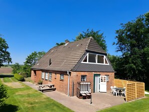 A brick house with a sloped roof, a front porch, and a small patio area with outdoor furniture. - Holiday Home Drelsdorfer Forst with Private Terrace, Garden and Wi-Fi (Drelsdorf)