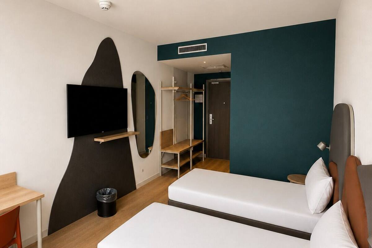A hotel room with two beds, a TV, a desk, and a wardrobe.