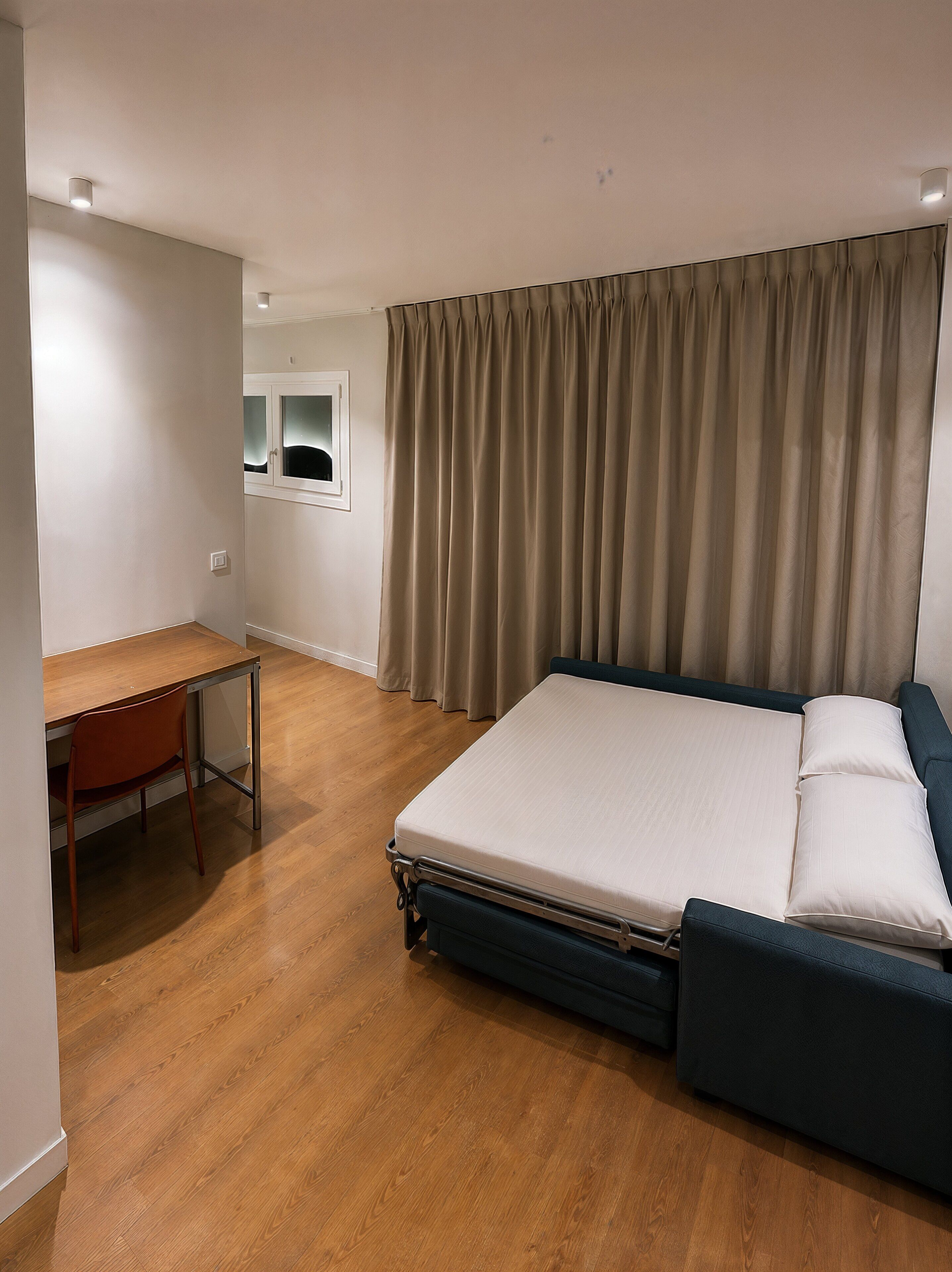 A hotel room with a bed, a desk, and a chair.
