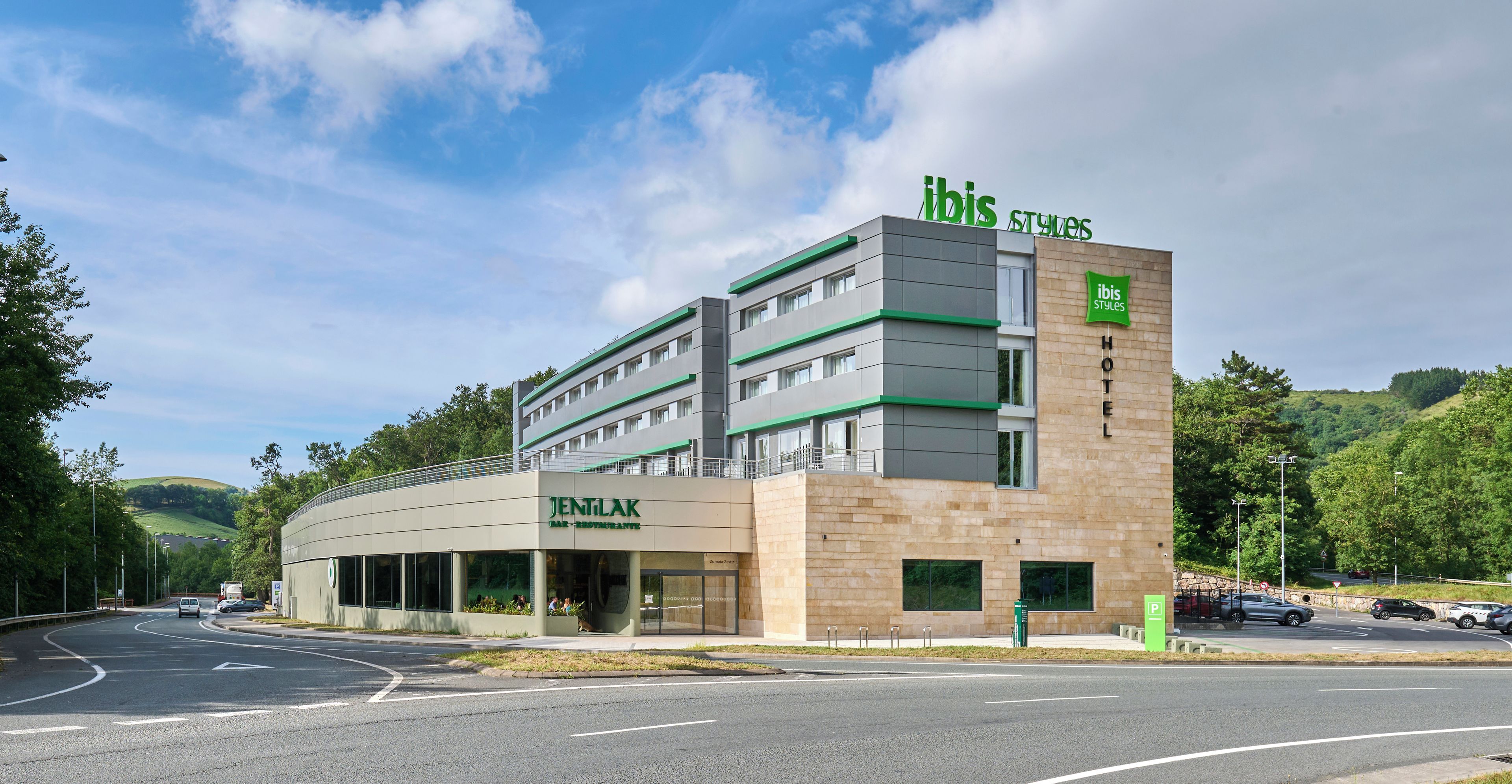 Un hotel moderno con un restaurante llamado 'JENTILAK' y un cartel que indica 'ibis Styles Hotel'.
