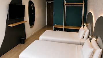 A modern hotel room with a large bed, a TV mounted on the wall, a wooden bench, and a small table.